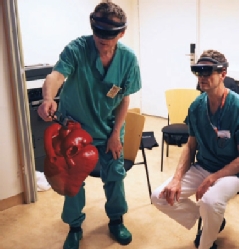 Figure 3. Brun et al. reproduced with permission. Shared view of heart hologram as used in surgical conference, similar to the evaluation study situation, with one person manipulating the model and the others looking at the process. The image is manipulated to show the heart model as it would be seen by a third spectator on the other side of the room. Reprinted with permission: Brun H, Bugge RAB, Suther LKR, et al. Mixed reality holograms for heart surgery planning: first user experience in congenital heart disease, European Heart Journal ¬ Cardiovascular Imaging 2019; 20(8): 883–888, doi:10.1093/ehjci/jey184